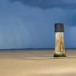 Phare isolé sur une plage déserte au crépuscule