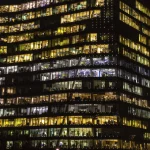 Immeuble de bureaux illuminé la nuit avec travailleurs visibles