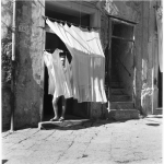 Homme derrière des draps suspendus devant une maison en ruine