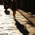 Femme marchant dans une rue pavée au coucher du soleil