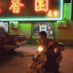 Homme sur un scooter devant un restaurant asiatique illuminé
