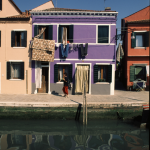 Maison colorée avec linge suspendu et femme passant devant le canal