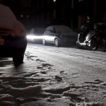 Rue enneigée de nuit avec voitures et lumières des phares