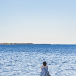 Femme Assise au Bord de l'Eau Contemplant l'Horizon