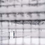 Terrain de tennis enneigé à travers un grillage