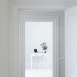 Vue à travers les portes vers un bureau blanc décoré de fleurs