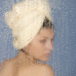 Femme avec serviette derrière une vitre mouillée
