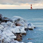 Littoral glacé avec phare rouge dans le lointain