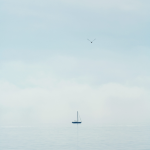 Voilier solitaire sur une mer calme sous un ciel embrumé