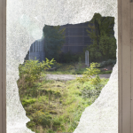 Fenêtre cassée avec vue sur un jardin abandonné