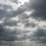 Ciel nuageux avec rayons de soleil au-dessus d'un lac