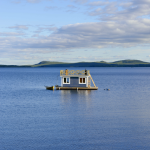 Maison flottante sur un lac paisible avec collines en arrière-plan