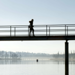 Personne marchant sur un pont au-dessus d'un lac par matin brumeux