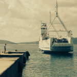 Ferry arrivant au quai avec groupe de personnes regardant