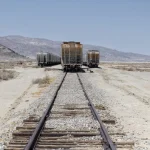 Wagons abandonnés sur une voie ferrée dans un désert montagneux
