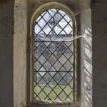 Fenêtre ancienne avec vitrail et toiles d'araignées