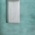 Fenêtre fermée sur un mur turquoise avec carreaux de sol décoratifs