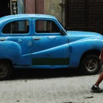 Femme marchant près d'une vieille voiture bleue