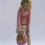 Fille riant avec un sac à main jouet