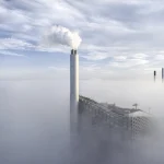 Centrale électrique dans le brouillard avec cheminées émergeant au-dessus des nuages