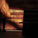 Personne en manteau orange près d'un mur texturé dans un espace sombre