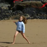 Fille jouant avec un cerf-volant sur une plage rocheuse