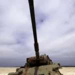 Tank abandonné sur une plage sous un ciel nuageux