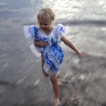 Enfant jouant sur la plage en robe bleue