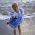Fillette en robe bleue sur la plage