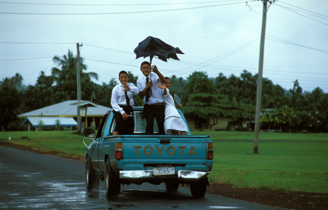 AKG883897.webp Trois enfants sur une camionnette avec un parapluie – Image 1