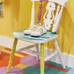 Chaise colorée avec des chaussures blanches sur sol multicolore