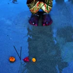 Fleurs et encens sur le sable avec pieds en arrière-plan