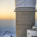 Observatoire astronomique sur fond de montagnes enneigées au coucher du soleil