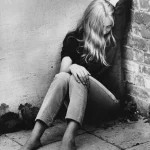 Fille assise contre un mur en noir et blanc