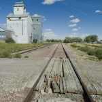 Voie ferrée désaffectée menant à un entrepôt abandonné.