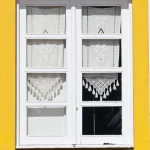Fenêtre blanche avec rideaux crochet sur mur jaune et blanc