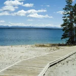Promenade en bois bordant un lac avec ciel bleu et nuages