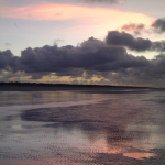 Coucher de soleil sur une plage déserte avec ciel nuageux