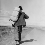 Homme marchant avec un grand sac à dos sur une route de campagne