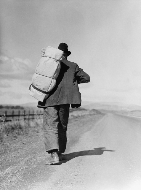 AKG896694.webp Homme marchant avec un grand sac à dos sur une route de campagne – Image 1