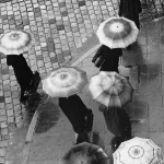 Piétons avec parapluies sur rue pavée