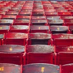 Vieilles chaises en bois rouge et bleu numérotées dans un stade désert