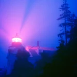 Phare illuminé dans le brouillard nocturne