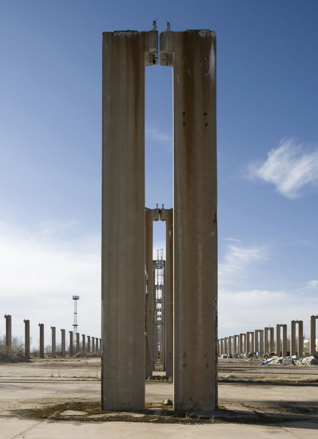 AKG900439.webp Colonnes de béton abandonnées sous un ciel bleu – Image 1