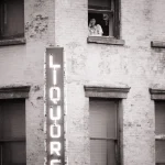 Personne à la fenêtre d'un immeuble avec enseigne de liquor store