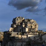 Église sur colline rocheuse sous ciel nuageux