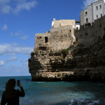 Femme photographiant une forteresse en bord de mer