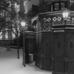 Kiosque ancien en noir et blanc devant un bâtiment historique enneigé