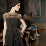 Modèle sur le podium portant une robe noire élégante.