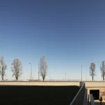 Personne marchant près d'un bâtiment sous un ciel clair avec des arbres en arrière-plan